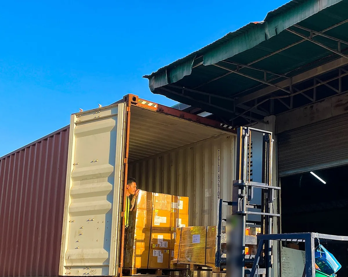 Shipping container being unloaded at a warehouse dock (stock photo)